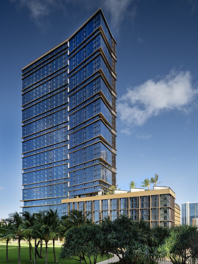 A tall building with many windows is surrounded by greenery.